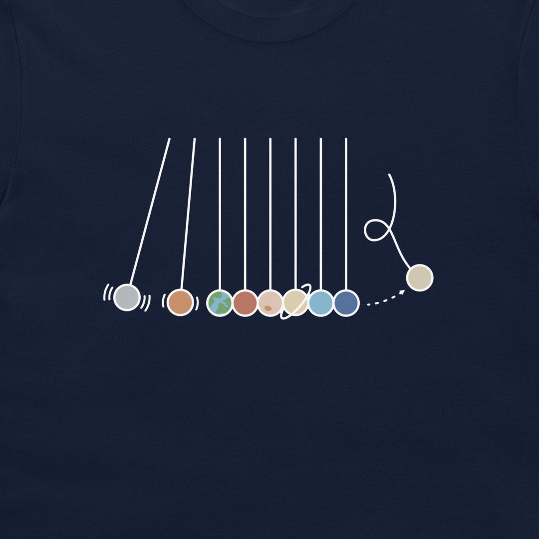 A close-up of a navy blue t-shirt featuring a white line-art graphic of a Newton's cradle with colorful balls.