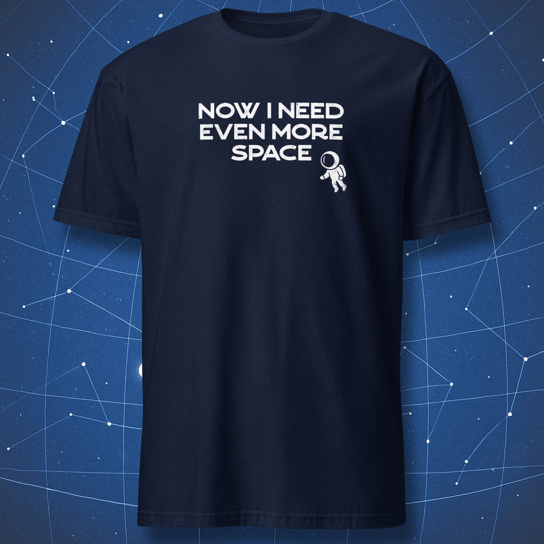 Navy blue t-shirt with 'Now I need even more space' text and astronaut graphic on a starry night sky background.  A cosmic nerd tee from DorkMatter.