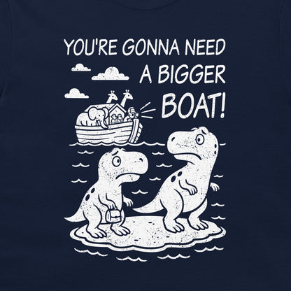 A navy blue t-shirt featuring a white graphic print of two dinosaurs sitting on a rock, with Noah's Ark in the background and the text 'YOU'RE GONNA NEED A BIGGER BOAT!'.