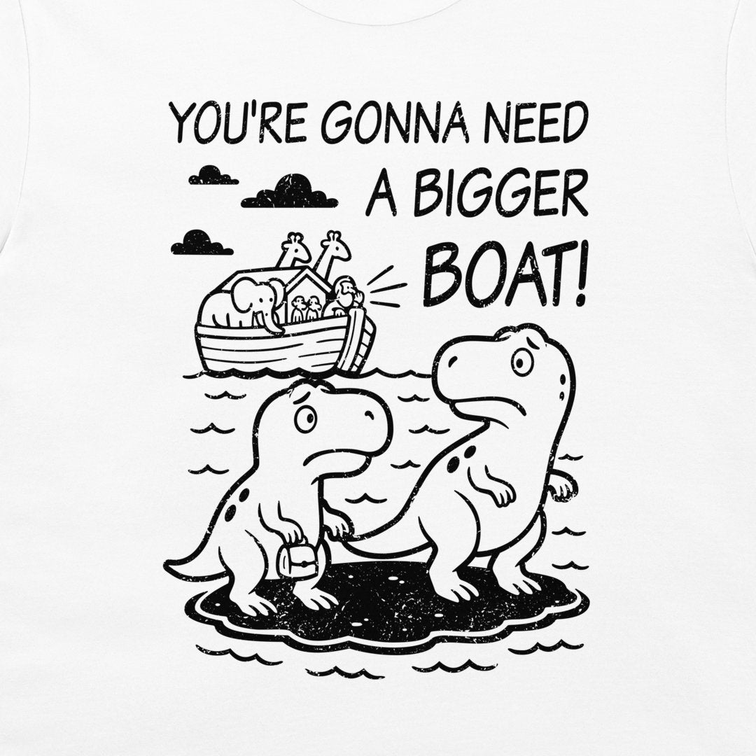 A close-up of a white t-shirt featuring a black graphic print. The design shows two cartoon dinosaurs standing on a small island, with Noah's Ark depicted in the background under clouds and the text 'YOU'RE GONNA NEED A BIGGER BOAT!'.