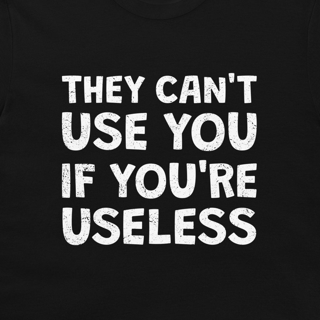 A close-up of a black t-shirt featuring a bold, distressed white text graphic that reads 'THEY CAN'T USE YOU IF YOU'RE USELESS'.