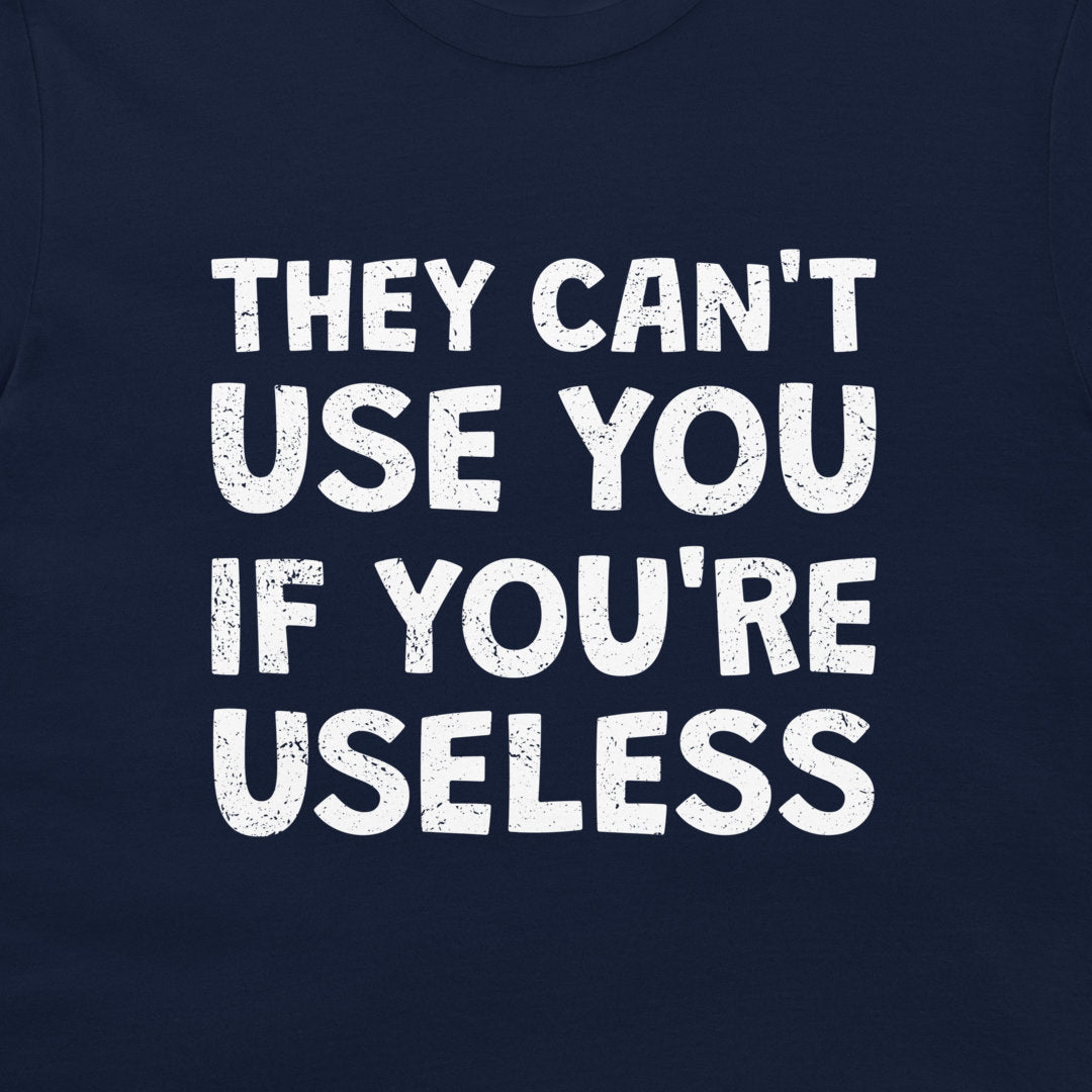 A close-up of a navy blue t-shirt featuring a bold, distressed white text graphic that reads 'THEY CAN'T USE YOU IF YOU'RE USELESS'.