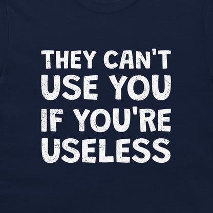 A close-up of a navy blue t-shirt featuring a bold, distressed white text graphic that reads 'THEY CAN'T USE YOU IF YOU'RE USELESS'.