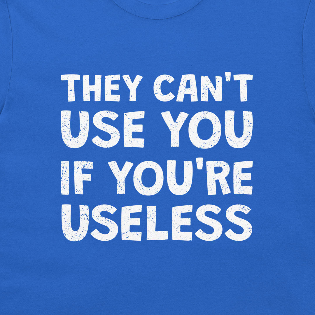 A close-up of a royal blue t-shirt featuring a bold white graphic text that reads 'THEY CAN'T USE YOU IF YOU'RE USELESS' in a distressed, stencil-like font.