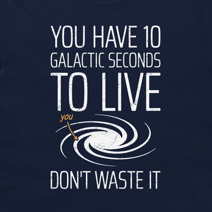 A close-up of a navy blue t-shirt featuring a white distressed graphic that reads 'YOU HAVE 10 GALACTIC SECONDS TO LIVE DON'T WASTE IT' with a spiral galaxy illustration and a small orange arrow pointing to the word 'you'.