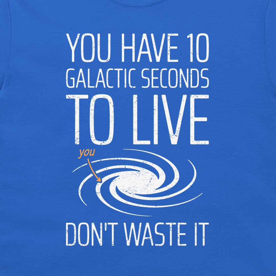 A close-up of a blue graphic t-shirt featuring white distressed text that reads 'YOU HAVE 10 GALACTIC SECONDS TO LIVE DON'T WASTE IT' with a white spiral galaxy illustration and a small orange arrow pointing to the word 'you'.