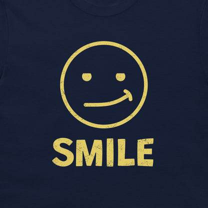 A close-up of a navy blue t-shirt featuring a distressed yellow graphic of a smiling face with the word 'SMILE' printed below it.