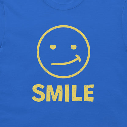 A close-up of a royal blue t-shirt, featuring a distressed yellow graphic of a smiling face and the word 'SMILE' printed below it.