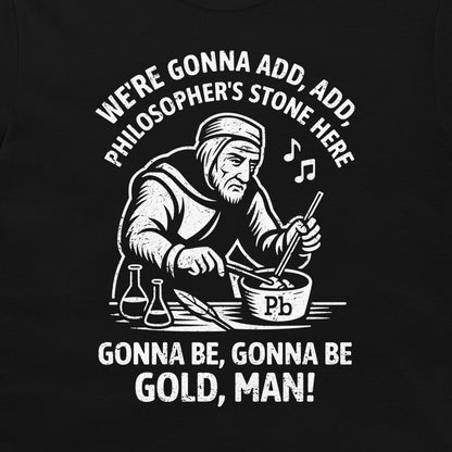 A  graphic print on a black t-shirt featuring a white illustration of a bearded man in historical robes mixing a bowl of lead (Pb) with a rod, surrounded by text that reads 'WE'RE GONNA ADD, ADD, PHILOSOPHER'S STONE HERE' and 'GONNA BE, GONNA BE GOLD, MAN!'.