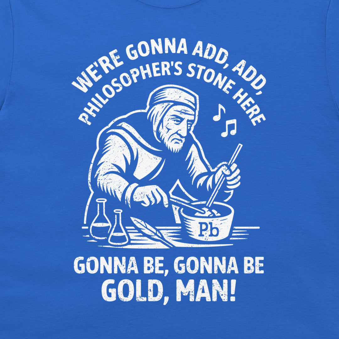 A close-up of a blue T-shirt featuring a white graphic print of a philosopher mixing gold powder in a bowl, with the text 'WE'RE GONNA ADD, ADD, PHILOSOPHER'S STONE HERE' and 'GONNA BE, GONNA BE GOLD, MAN!'.