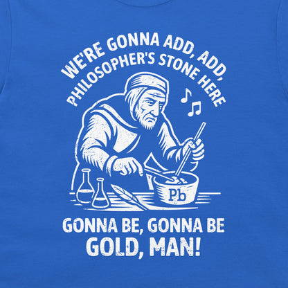 A close-up of a blue T-shirt featuring a white graphic print of a philosopher mixing gold powder in a bowl, with the text 'WE'RE GONNA ADD, ADD, PHILOSOPHER'S STONE HERE' and 'GONNA BE, GONNA BE GOLD, MAN!'.