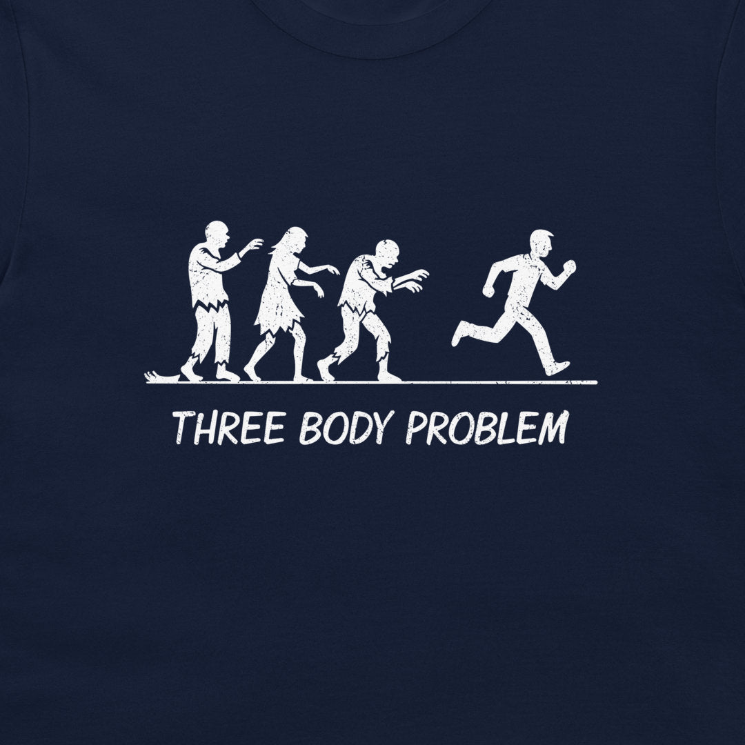 A close-up of a navy blue t-shirt featuring a white graphic print of the 'Three Body Problem' concept, showing three zombies chasing  a running man, with the text 'THREE BODY PROBLEM' printed below.