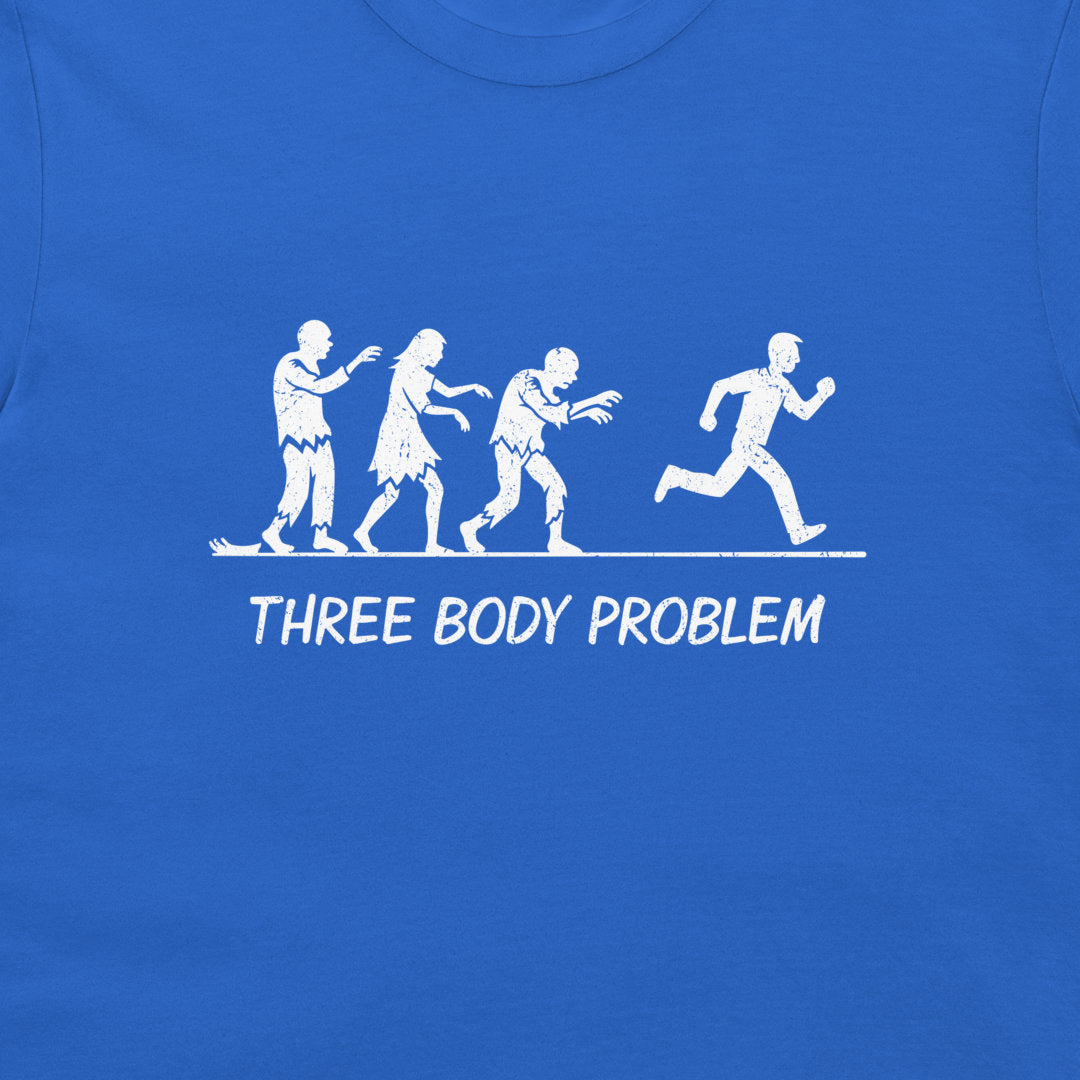 A close-up of a blue t-shirt featuring a white graphic print of the 'Three Body Problem' concept, showing three zombies chasing  a running human silhouette, with the text 'THREE BODY PROBLEM' printed below.