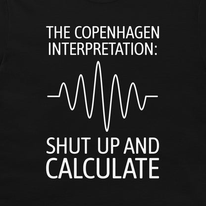 A close-up of a black t-shirt, featuring a white graphic print that reads 'THE COPENHAGEN INTERPRETATION: SHUT UP AND CALCULATE' with a white heartbeat-style waveform line in the center.