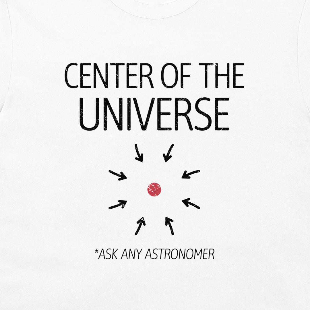 White t-shirt featuring a black graphic print that reads 'CENTER OF THE UNIVERSE' with arrows pointing toward a small red dot, and the text '*ASK ANY ASTRONOMER' below.