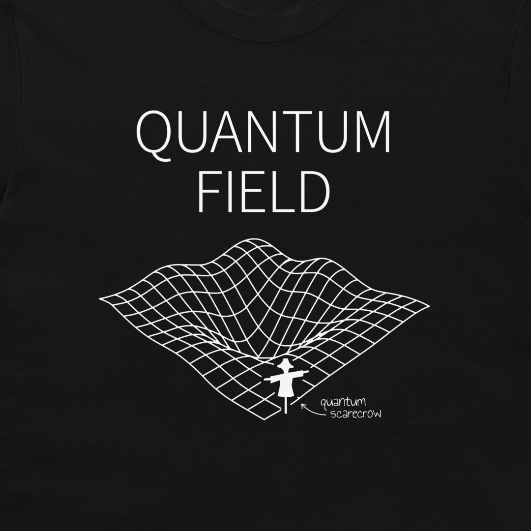 A close-up of a black garment, likely a t-shirt, featuring a white graphic print of the word 'QUANTUM FIELD' above a 3D grid surface with a small figure and the text 'quantum scarborough'.