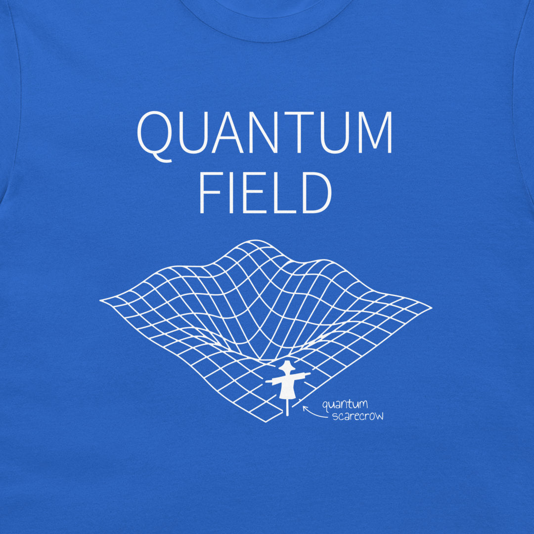 A close-up of a blue t-shirt featuring a white graphic print of the word 'QUANTUM FIELD' above a 3D grid surface with a small figure labeled 'quantum scarcrow'.