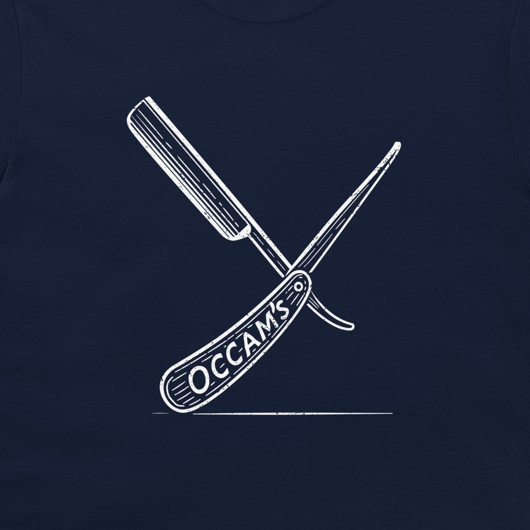 A close-up of a navy blue garment, likely a t-shirt, featuring a white graphic of two crossed folding knives with the word 'OCCAMS' printed on the handle.