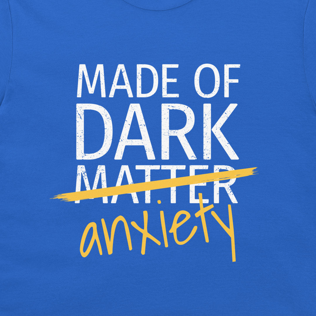 A close-up of a blue graphic print on a garment. The design features the distressed white text 'MADE OF DARK MATTER' crossed out with a yellow brush stroke, with 'anxiety' written below in yellow script.