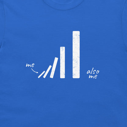A close-up of a royal blue t-shirt featuring a white distressed graphic of falling dominoes with the handwritten words 'me' and 'also me'.
