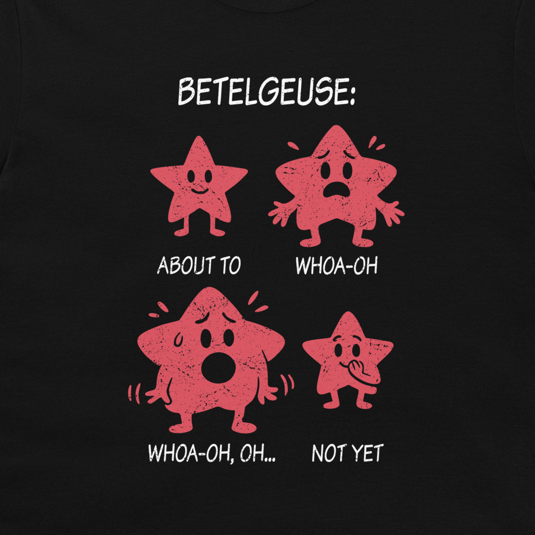 A close-up of a black garment featuring a red and white graphic print. The graphic shows four cartoon star characters in different expressions with humorous German phrases: 'BETELGEUSE:', 'ABOUT TO', 'WHOA-OH', 'WHOA-OH, OH...', 'NOT YET'.