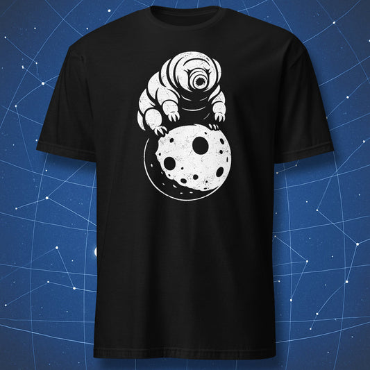 White minimalist tardigrade illustration sitting on a cratered moon on a black T-shirt.
