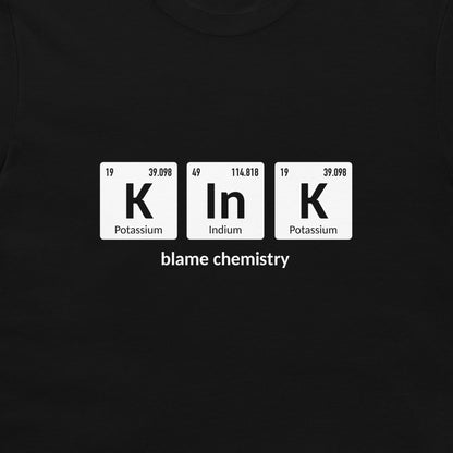 A black crewneck t-shirt featuring a white graphic of three periodic table style tiles spelling 'K In K' with the text 'blame chemistry' underneath.