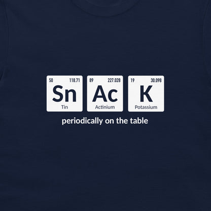 A close-up of a navy blue t-shirt featuring a white graphic of three periodic table tiles spelling 'SnAcK' with the phrase 'periodically on the table' underneath.