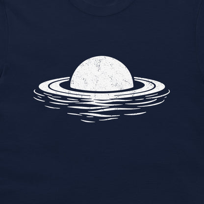 A close-up of a dark navy blue t-shirt featuring a distressed white graphic of a planet with rings floating in water.