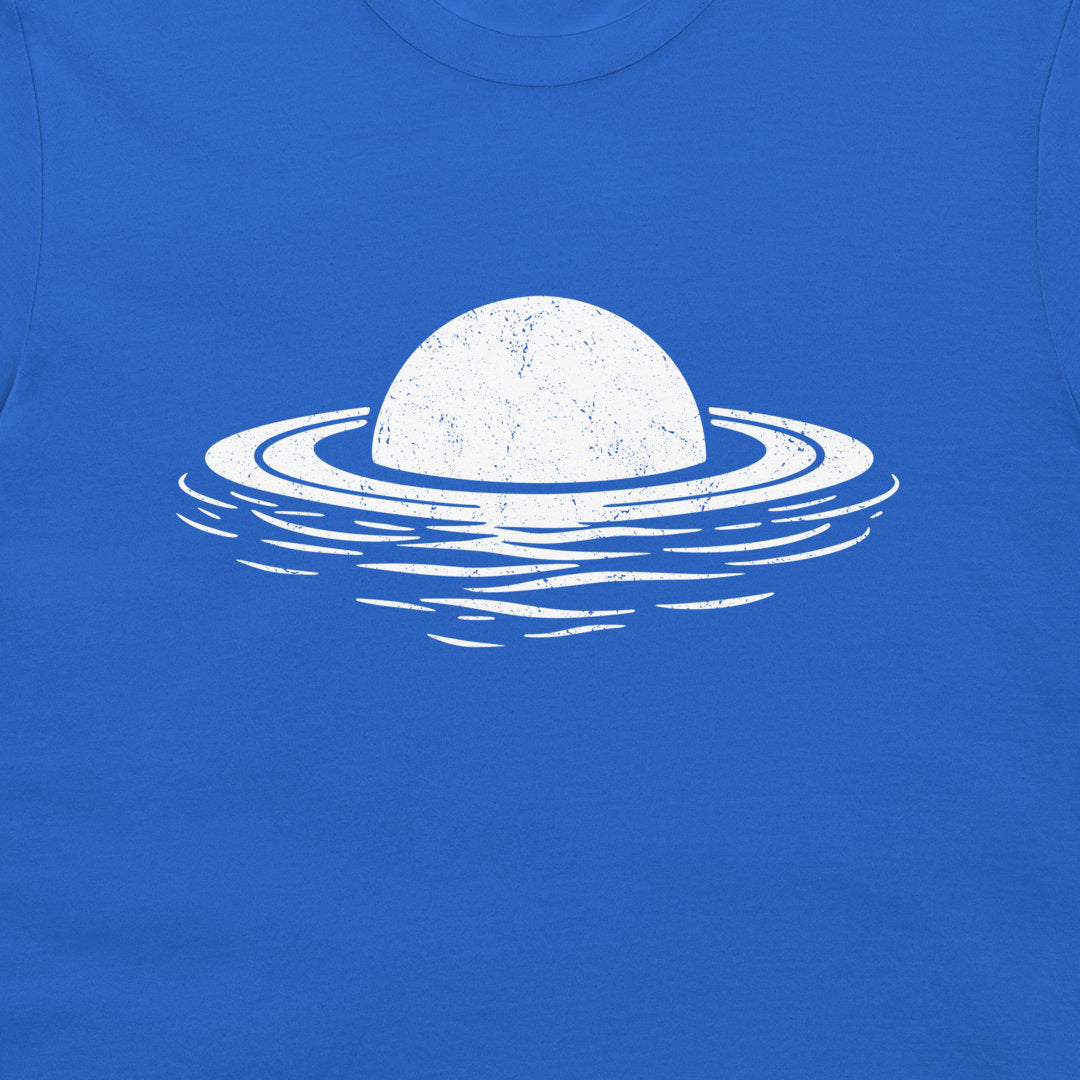 A close-up of a bright blue t-shirt featuring a distressed white graphic of a planet with rings floating on water.