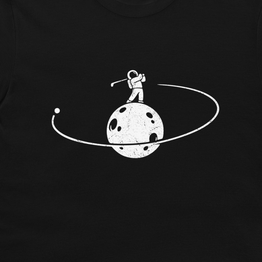 A close-up of a black t-shirt, featuring a white distressed graphic of an astronaut standing on a cratered moon with an orbit ring.