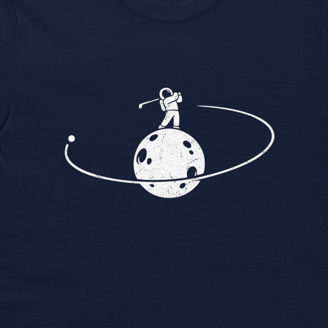A close-up of a navy blue t-shirt featuring a distressed white graphic of an astronaut standing on a cratered moon with a ring around it.