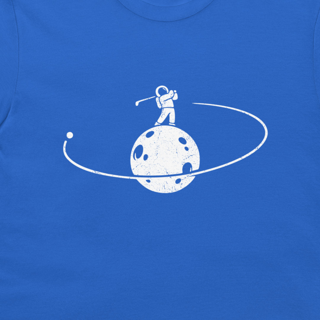 A close-up of a royal blue t-shirt featuring a white distressed graphic of an astronaut playing golf on a cratered moon with an orbit ring.