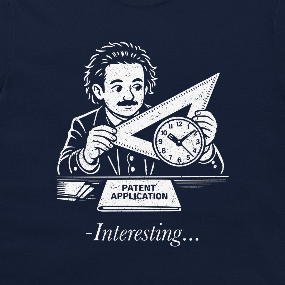 A navy blue t-shirt featuring a white graphic print of Albert Einstein holding a triangular ruler and a clock, with the text 'PATENT APPLICATION' and '-Interesting.