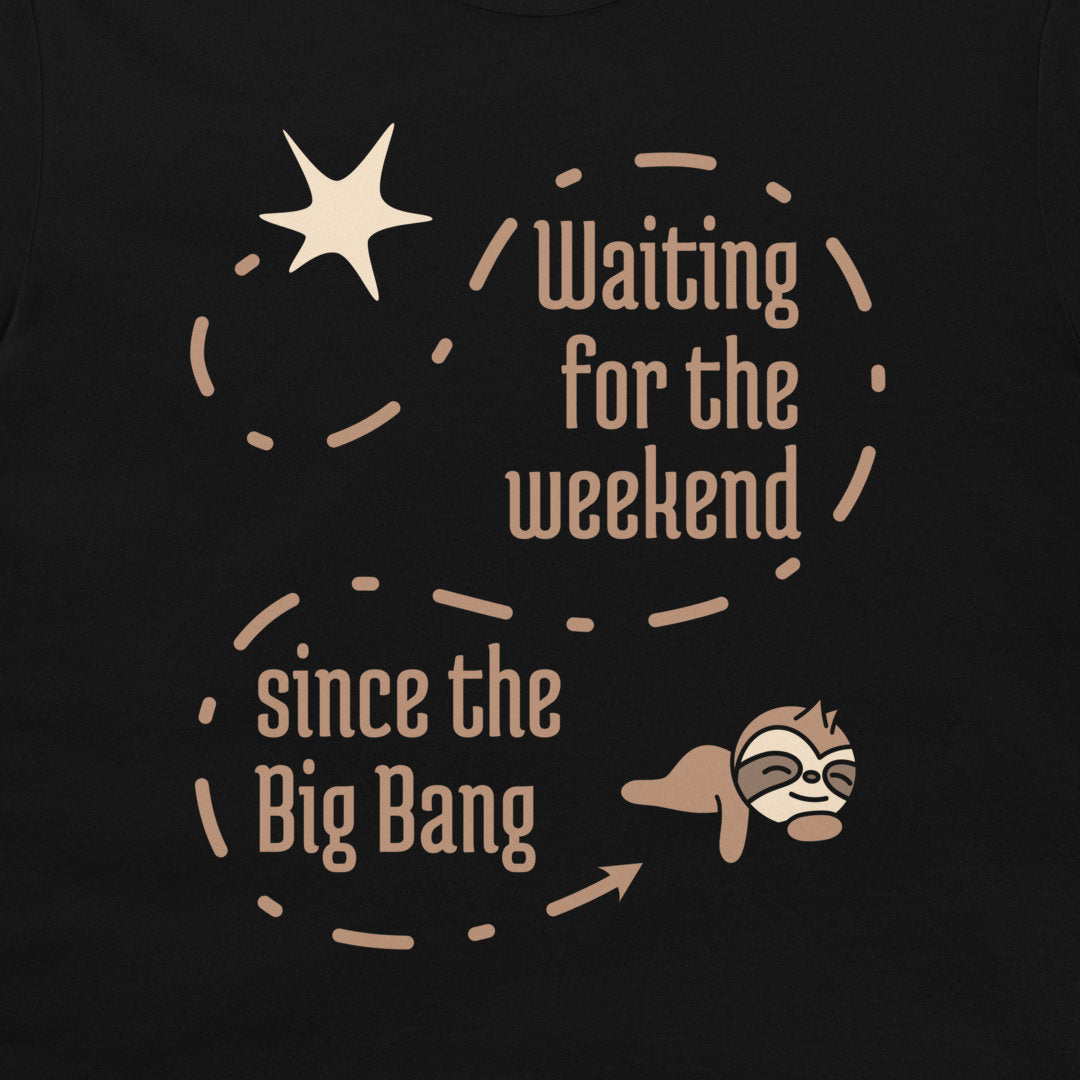 A close-up of a black t-shirt featuring a graphic design with the text 'Waiting for the weekend since the Big Bang' in a warm beige font, accompanied by a star, dashed circular line, and a cartoon sloth.