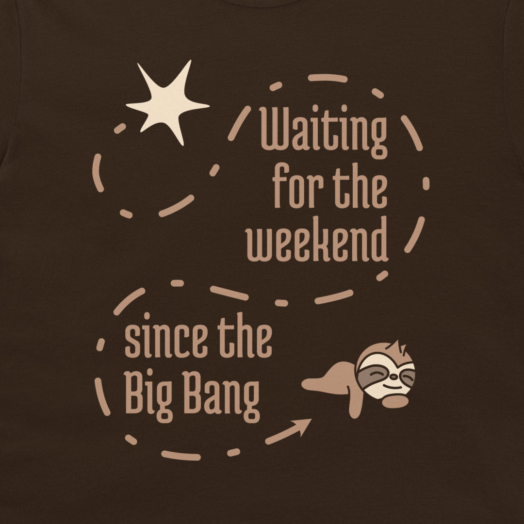 A close-up of a dark brown t-shirt featuring a graphic design with the text 'Waiting for the weekend since the Big Bang' in a light beige font, accompanied by a star, dashed circular line, and a cartoon sloth.