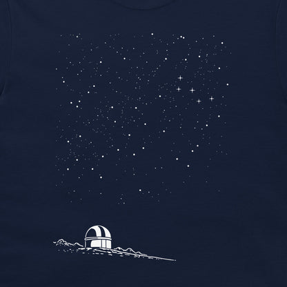 A close-up of a navy blue garment, likely a t-shirt, featuring a white graphic print of a small observatory dome on a mountain ridge beneath a starry night sky.