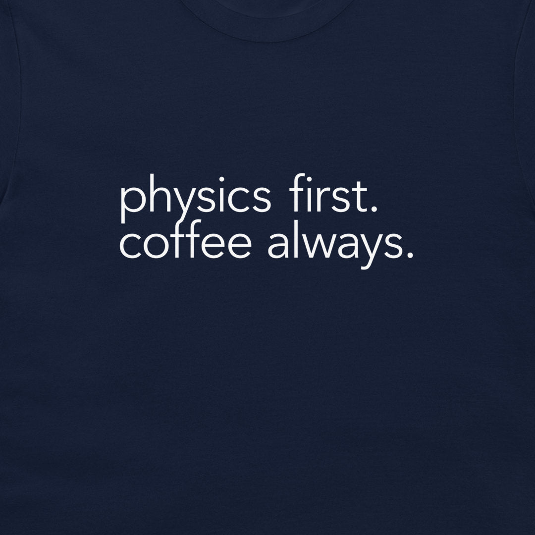 A close-up of a navy blue t-shirt featuring the phrase 'physics first. coffee always.