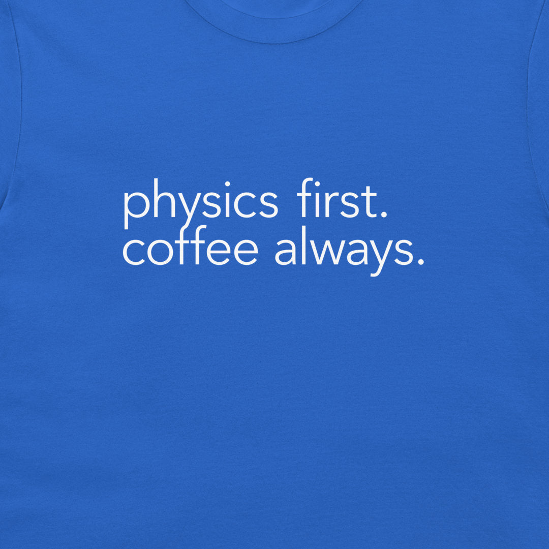 A close-up of a blue t-shirt featuring the printed white text 'physics first. coffee always.' in a clean sans-serif font.