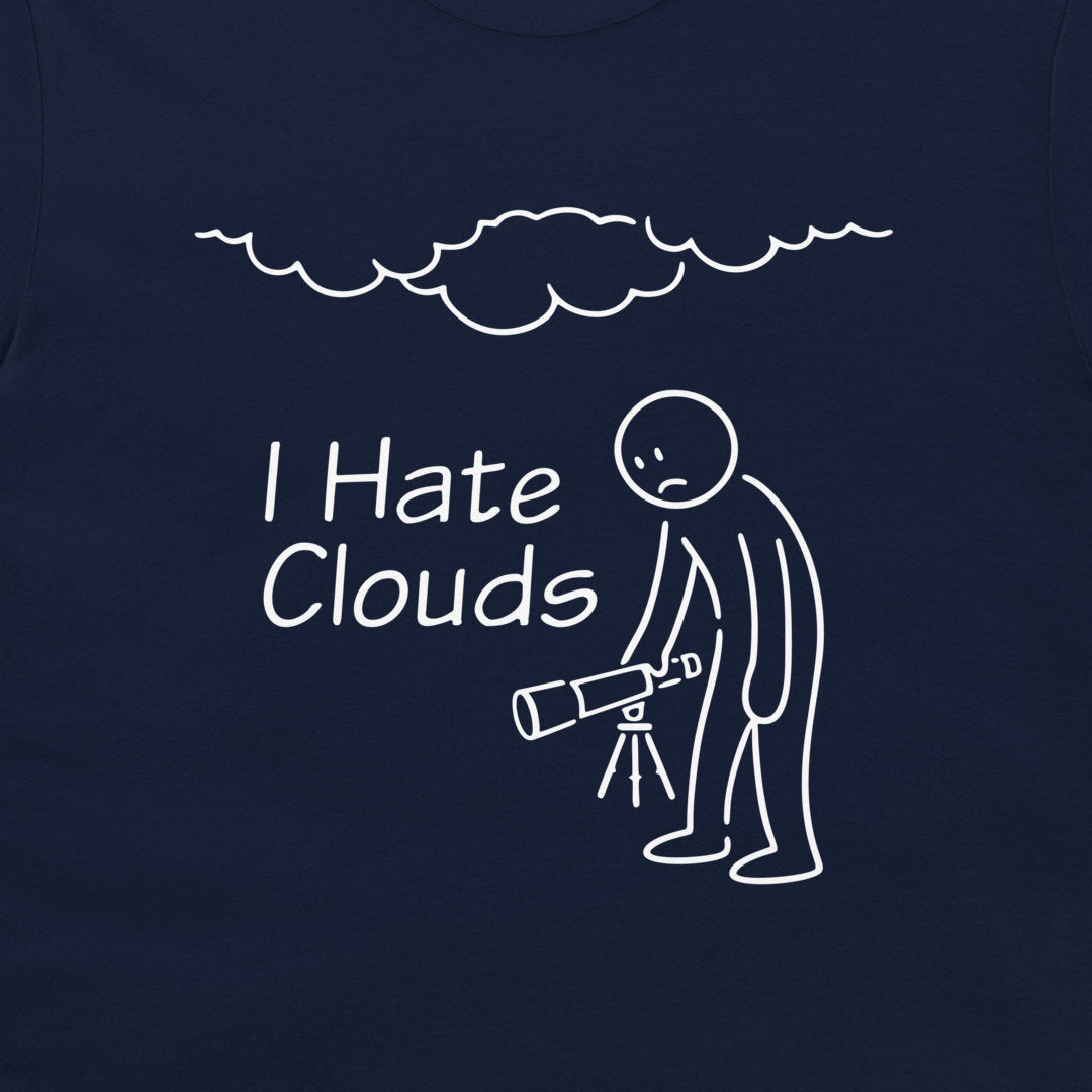 A close-up of a navy blue t-shirt, featuring a white graphic print. The design shows a stick figure holding a telescope under a cloud, with the text 'I Hate Clouds'.