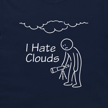 A close-up of a navy blue t-shirt, featuring a white graphic print. The design shows a stick figure holding a telescope under a cloud, with the text 'I Hate Clouds'.