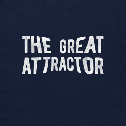 A close-up of a navy blue t-shirt featuring the phrase 'THE GREAT ATTRACTOR' printed in a distressed white typewriter-style font across the chest.