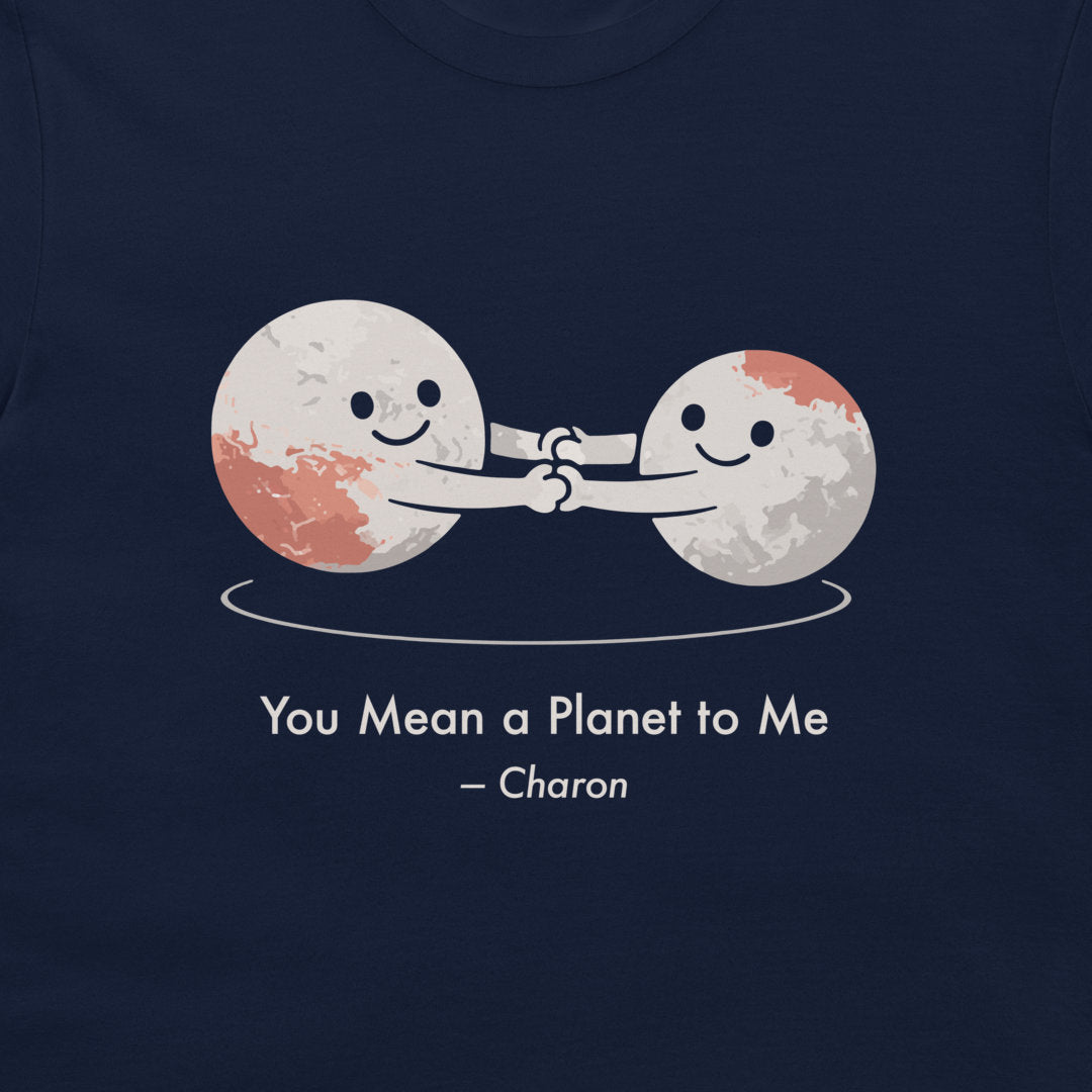 A close-up of a navy blue t-shirt featuring a graphic of two smiling cartoon celestials holding hands, with the text 'You Mean a Planet to Me - Charon' printed below in white.