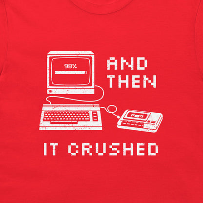 A close-up of a bright red t-shirt, featuring a white distressed graphic of retro computer and cassette tape illustrations with the text 'AND THEN IT CRUSHED'.