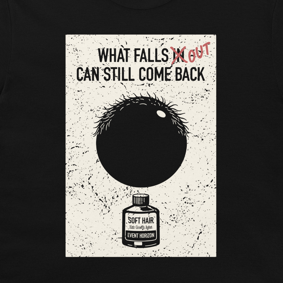 A black crewneck t-shirt featuring a distressed white rectangular graphic print. The graphic displays the text 'WHAT FALLS IN CAN STILL COME BACK' with 'IN' crossed out in red scribble, and written 'OUT' next to it. Below there is a black circle representing a hair follicle and a black hole in the same time, and an illustration of a small bottle labeled 'SOFT HAIR'.