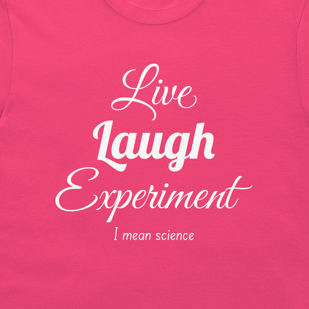 A close-up of a bright pink t-shirt featuring the text 'Live Laugh Experiment I mean science' printed in white script and serif fonts.