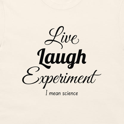 A close-up of a light cream-colored t-shirt featuring a black printed graphic that reads 'Live Laugh Experiment I mean science' in stylized fonts.