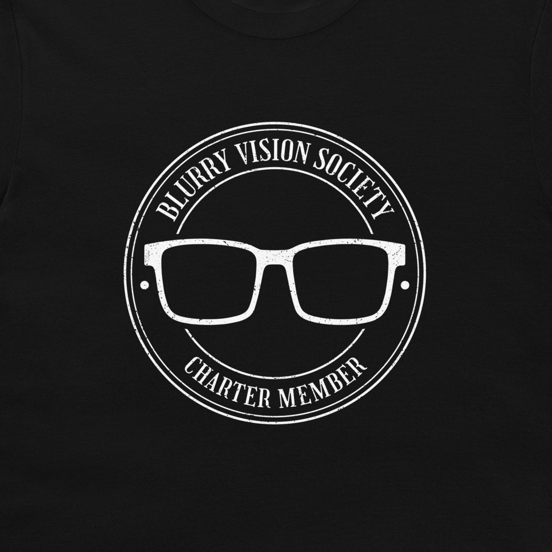 A close-up of a black garment featuring a distressed white circular graphic with the text 'BLURRY VISION SOCIETY' and 'CHARTER MEMBER' surrounding a pair of glasses.