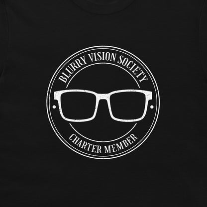 A close-up of a black garment featuring a distressed white circular graphic with the text 'BLURRY VISION SOCIETY' and 'CHARTER MEMBER' surrounding a pair of glasses.