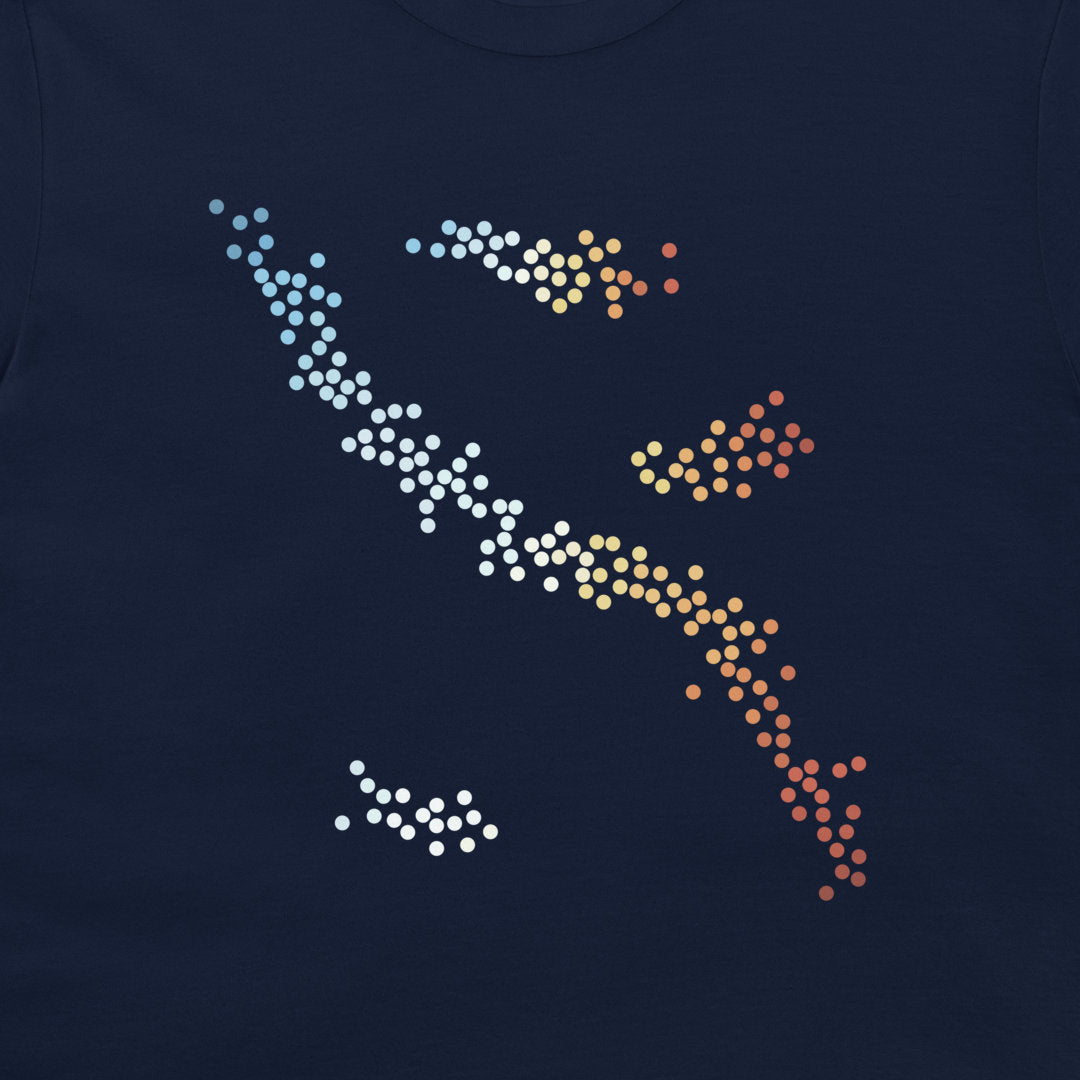 A close-up of a navy blue t-shirt featuring a stylized graphic of a fish made of white, yellow, orange, and red gradient dots.